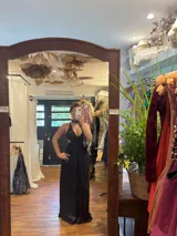 Vestido largo negro con escote en V, cut outs laterales bajo el busto y breteles finos cruzados y atados en la espalda.