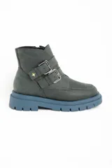 Bota corta de cuero color verde oscuro, con suela track gruesa de color celeste. Presenta dos correas ajustables con hebillas metálicas plateadas y un pequeño dije de estrella dorada en el lateral. Tiene cierre de cremallera en el interior.