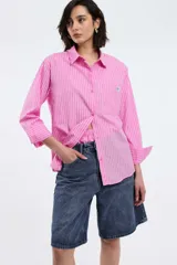 Camisa a rayas verticales rojas y blancas, de corte recto, con cuello clásico, manga larga y bolsillo en el pecho.