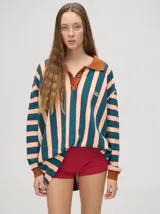 Chomba de algodón de corte oversize a rayas verticales color crema y verde azulado, con cuello camisero marrón, puños acanalados marrones y logo bordado en el pecho.