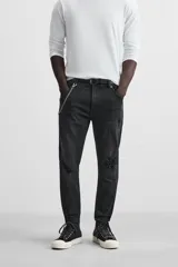 Pantalón de jean negro con corte skinny fit, cinco bolsillos, lavado con efecto roto y cierre frontal con cremallera y botón.
