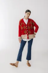 Cárdigan color beige con patrón de rombos en tonos marrones, cierre con botones, bolsillos frontales y bordados de cerezas.