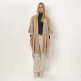Poncho calado color beige con flecos en el ruedo.