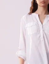 Blusa color beige de lino, marca Dash. Cuello a la base, escote en V y abertura con botones. Delantera con bolsillos. Largo de manga regulable con presilla y botón.