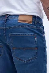 Jean azul de corte slim fit, con cintura media y cierre con botón y cremallera.