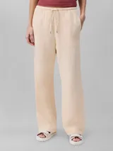 Pantalón de corte recto color beige, de gasa doble con textura arrugada, cintura elástica con cordón ajustable, bolsillos laterales y trasero.