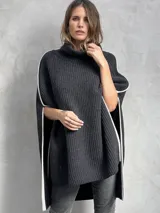 Poncho tejido de punto grueso color gris oscuro con cuello alto y ribete blanco en los bordes.