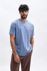 Remera celeste de manga corta con cuello redondo y estampado frontal con texto en color ladrillo.