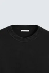 Sweater negro de punto con cuello redondo y mangas largas.