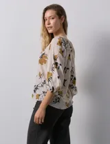 Blusa de gasa verde con estampado floral blanco y celeste, cuello a la base con escote en V y mangas 3/4 fruncidas.