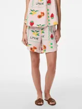 Short de tiro alto con cintura elástica y detalles de volantes, confeccionado en tejido plano de mezcla de lino, algodón y viscosa. Presenta un diseño holgado con estampado multicolor de limones, frutillas y texto sobre fondo rosado.