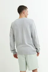 Sweater gris de punto con escote en V y mangas largas.