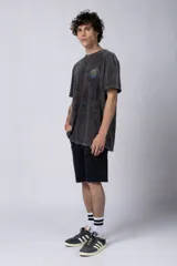 Remera de hombre color gris oscuro con efecto gastado (snow wash), corte semi-oversize y un pequeño estampado circular en el pecho que simula una obra de arte.