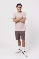 Remera de algodón color rosa pálido, con cuello redondo y manga corta. Presenta un pequeño texto estampado en el pecho.