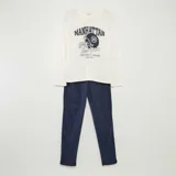 Conjunto de pijama largo de punto, compuesto por una remera blanca de manga larga con estampado de casco de fútbol americano y un pantalón azul marino liso.