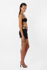 Minifalda negra de microfibra con tiro bajo, corte ajustado y frunces en el delantero. Incluye panty de microtul unida a la falda mediante tiras y argolla.