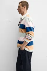 Polo de manga larga con cuello clásico y cierre de botones oculto. Diseño a rayas horizontales en colores azul, naranja, rosa y verde.
