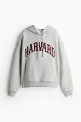 Canguro gris con capucha y cordones ajustables, bolsillo tipo canguro y puños y bajo acanalados. Estampado frontal con el nombre "Harvard" en color bordó.