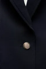 Blazer negra entallada con cuello solapa, manga larga con hombreras, bolsillos delanteros con solapa y cierre frontal con botones dorados.