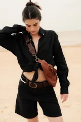 Camisa negra de lino con cuello clásico, manga larga y cierre frontal con botones. Presenta un bordado con un caballito, un sol y la bandera de Uruguay en el frente.