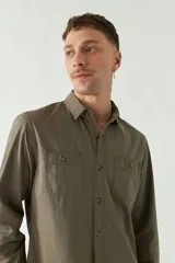 Camisa de gabardina gris con corte slim, mangas largas, cartera abotonada y dos bolsillos con solapa en el pecho.