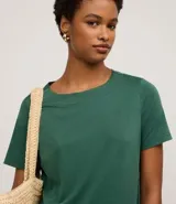 Vestido corto de mujer, estilo camiseta, color terracota/óxido, con escote redondo, mangas cortas y bolsillos laterales. El bajo es redondeado.