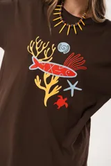 Remerón oversize de algodón color chocolate con estampado de motivos marinos en tonos rojo, amarillo, azul y blanco.