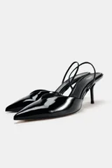 Zapato destalonado de charol negro con escote en pico, tira trasera ajustable y tacón fino.