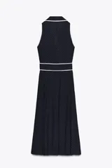 Vestido midi azul marino con estampado de lunares blancos, cuello solapa, escote en pico y sin mangas. Incluye cinturón de la misma tela y cierre frontal con botones.