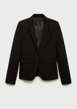 Chaqueta negra con cuello de pico con solapa y cierre de botón en la parte delantera. Tiene manga larga con puños abotonados, diseño recto, estilo traje y dos bolsillos de solapa en la parte delantera.