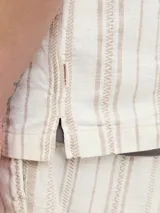 Camisa de manga corta con botones, cuello resort y corte relajado. Diseño a rayas verticales color beige y blanco.