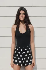 Shorts negros con estampado de lunares blancos, de tiro alto y cierre lateral con cremallera oculta.