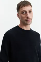 Buzo de punto color beige, con cuello redondo y mangas largas. Tejido con textura piquet y puños acanalados. Corte regular.