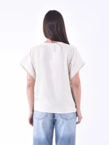 Blusa negra con estampado de ramas en color crema, escote en V y mangas cortas con dobladillo.