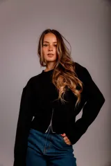 Buzo negro de punto con cierre frontal plateado, cuello redondo y mangas largas.