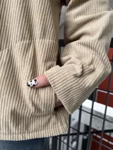 Campera de pana color beige con cierre frontal y cuello negro.