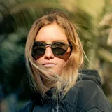 Lentes de sol Indie Hill con montura redonda de madera color marrón oscuro y lentes verdes. Patillas de madera clara.