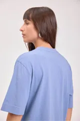 Remera color tostado de algodón con cuello redondo y mangas cortas. Estampado pequeño en el centro del pecho con un sol y texto.