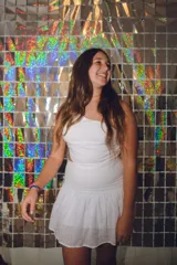 Vestido corto blanco con un hombro descubierto, pieza fruncida en la espalda, cut out en cintura y espalda con top y pollera separados. Falda con corte en caderín y volado, y un bretel fino que se cruza en la espalda.