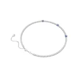 Collar rígido plateado con hilera de cristales blancos y tres cristales cuadrados azules. Cierre de mosquetón con cadena de alargue y dije de cisne. Colección Matrix de Swarovski.