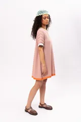 Vestido corto tipo remerón color rosa, de tejido de punto con cuello redondo y mangas cortas. Presenta ribetes en color amarillo en el cuello, celeste en las mangas y naranja en el ruedo.