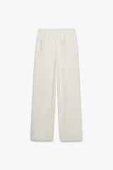 Pantalón de tiro alto color hueso, con bolsillos delanteros y traseros, cintura elástica ajustable con cordones y corte ancho.