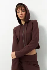 Campera corta negra con capucha, cierre frontal y cordones ajustables.