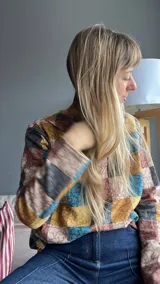 Sweater de punto con cuello alto y mangas largas, con diseño de bloques de colores en tonos marrón, beige, azul y amarillo.