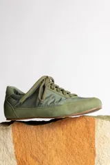 Zapatillas deportivas verde oliva con cordones y suela marrón.