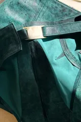 Top corto de cuero ovino color verde azulado con textura vintage, cuello halter y espalda descubierta con cierre de hebilla metálica. Combina con falda a juego.