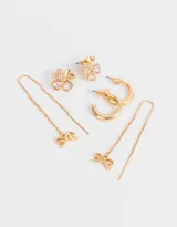 Set de tres pares de aros dorados: un par de aros tipo botón con forma de trébol de cuatro hojas con strass rosado, un par de aros tipo argolla gruesa y un par de aros colgantes con cadena y dije de moño.