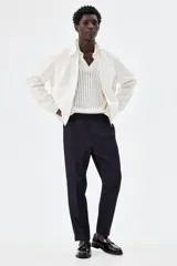 Pantalón tobillero azul marino de sarga suave con cintura elástica y cordón ajustable. Tiene bolsillos laterales y traseros ribeteados, piernas con pliegues cosidos y doblez en el bajo.