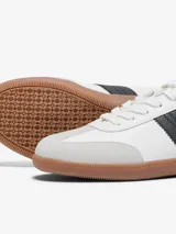 Zapatillas blancas con detalles en gris y una franja lateral negra. Suela de goma color caramelo.