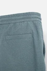 Bermuda azul de tejido con mezcla de algodón, corte relaxed fit, cintura elástica ajustable con cordón, bolsillos delanteros y detalle de bolsillo trasero de vivo.
